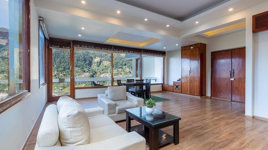 Shot of the seating area at the suite featuring white couches and a expansive window | DLS Serenity Resort and Spa